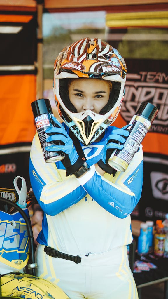 Motocross rider in gear holding lubricant spray cans promoting Liqui Moly.